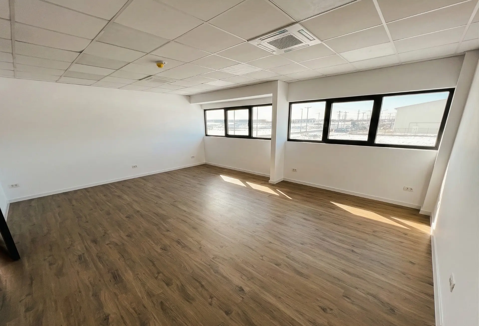 Bright empty office with wooden flooring and panoramic windows